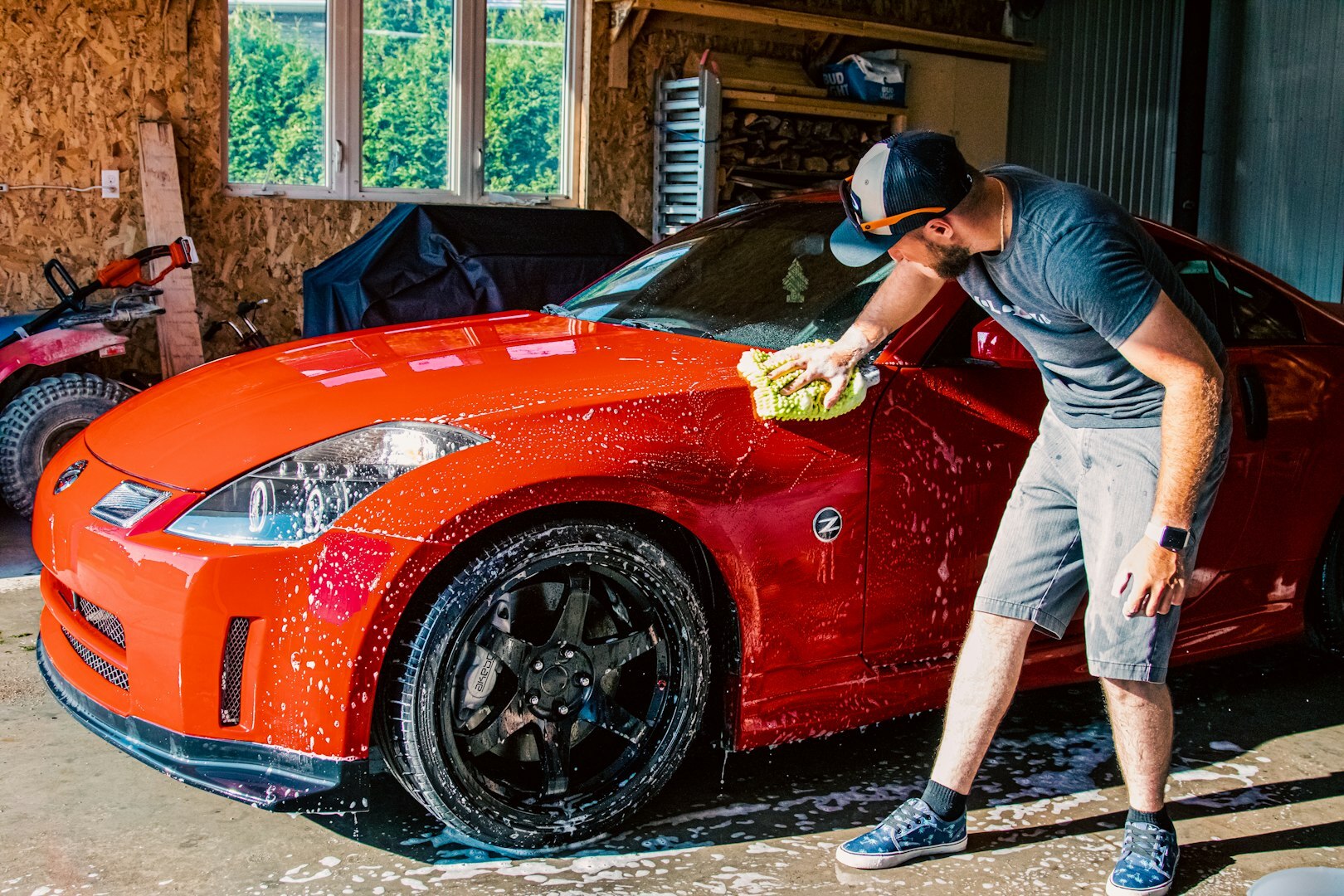 a man washing a red sports car in a garage a man washing a red sports car in a garage